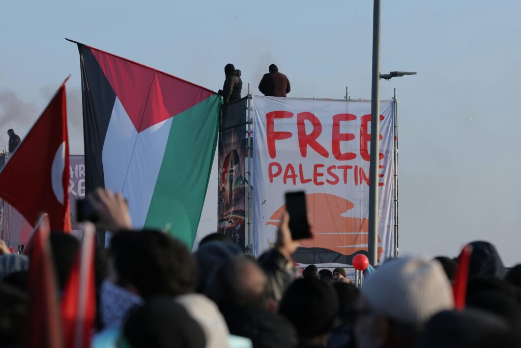 Crowd at İstanbul protest holding Palestinian flags advocating for freedom.